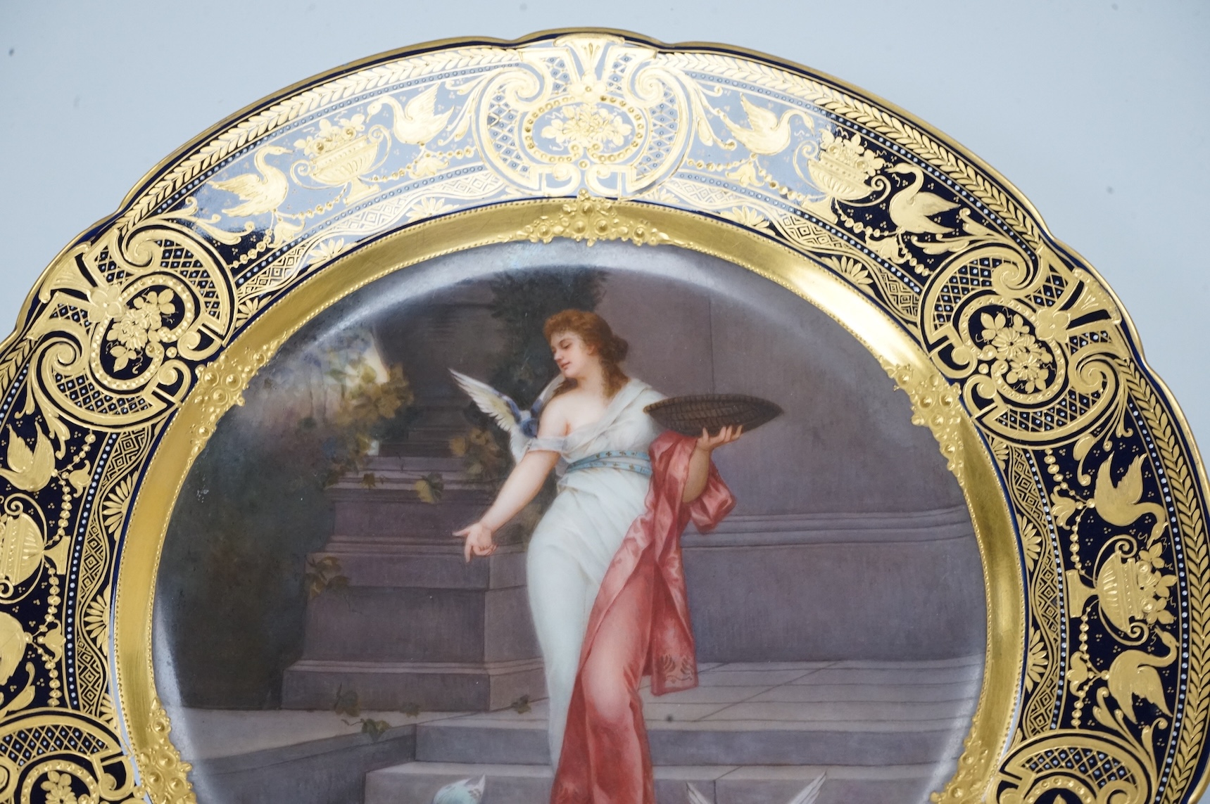 A Vienna-style cabinet plate, painted with a Vestal Virgin, after P. Wagner, depicting a lady feeding pigeons, signed Goget?, 24cm in diameter